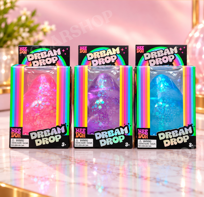 Three NeeDoh Dream Drop squishies in pink, purple and blue, each in its own rainbow-trimmed retail packaging.